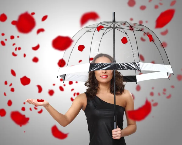 Mujer bonita bajo paraguas con pétalos a su alrededor — Foto de Stock