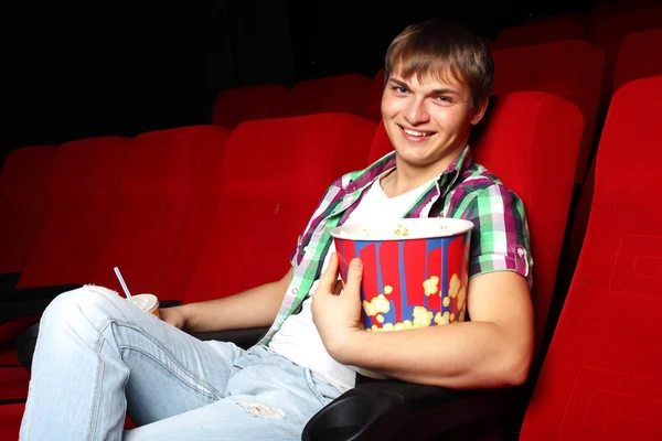 Nuori mies elokuvissa katsomassa elokuvaa — kuvapankkivalokuva