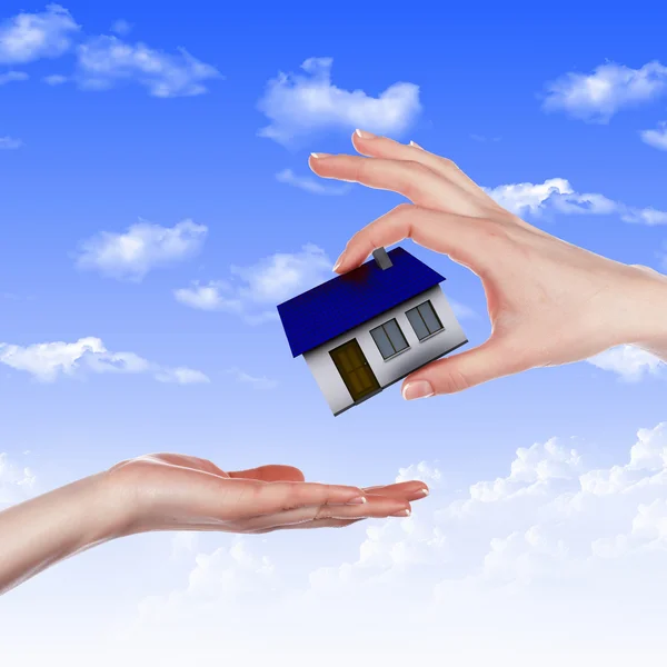 House and human hand against blue sky — Stock Photo, Image