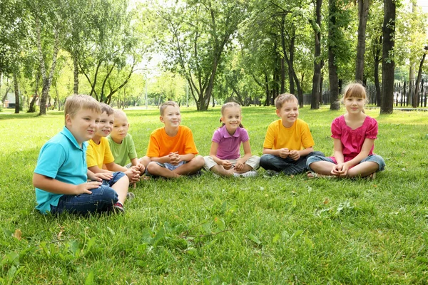 Група дітей, що сидять разом у парку — стокове фото