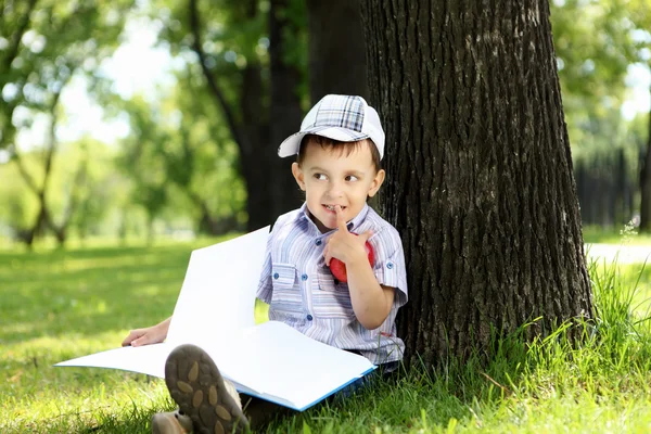 Portrait of a boy with a book in the park — Stock Photo, Image