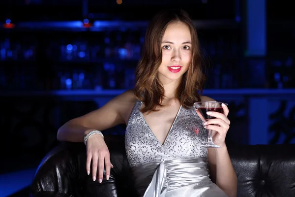 Mladá žena v nočním klubu s nápojem — Stock fotografie