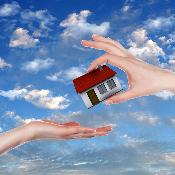 Дом и человеческая рука против голубого неба — стоковое фото