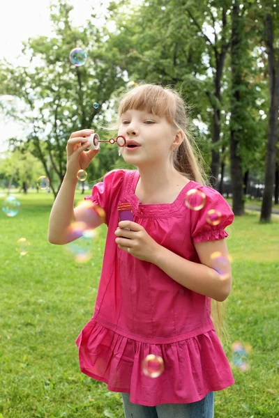 Menina no parque soprando bolhas — Fotografia de Stock