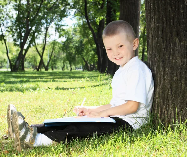 Porträt eines Jungen mit einem Buch im Park — Stockfoto