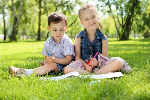 Crianças no parque lendo um livro — Fotografia de Stock