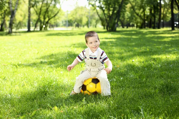 Malý chlapec v parku hrát s míčem — Stock fotografie