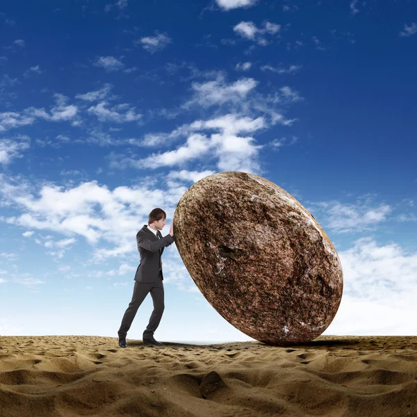 Бизнесмен катит гигантский камень — стоковое фото
