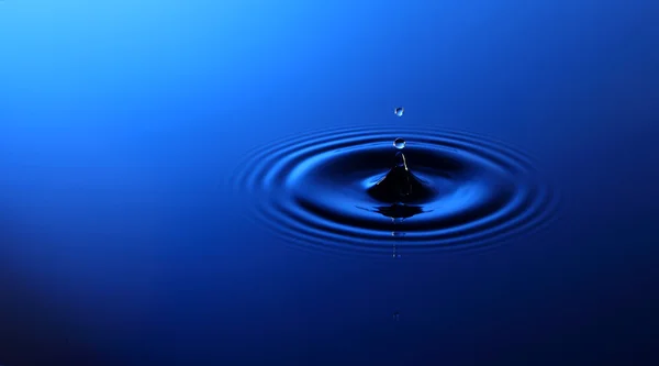 Drop of water falling into the water — Stock Photo, Image