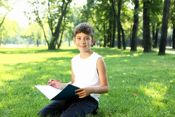 Πορτρέτο ενός αγοριού με ένα βιβλίο στο πάρκο — Φωτογραφία Αρχείου