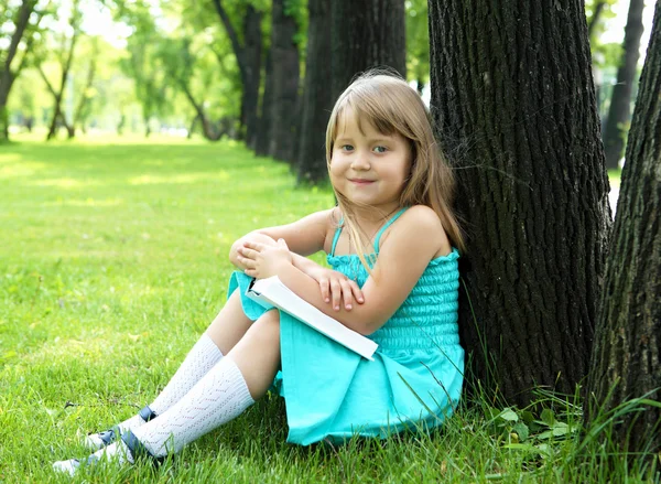 Porträtt av lilla flickan läsa en bok i parken — Stockfoto