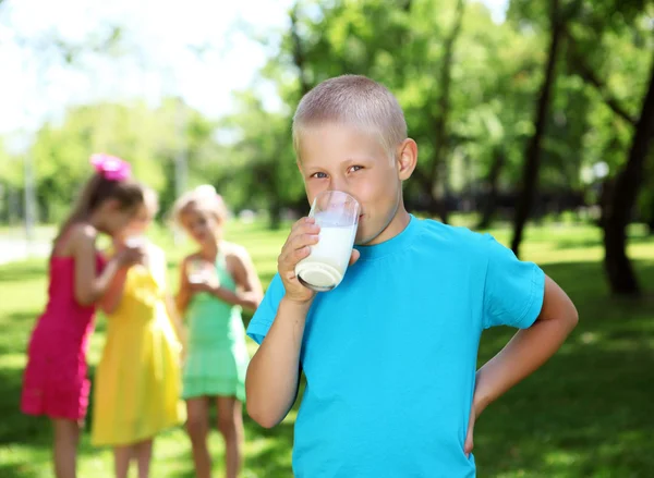 Menino bebendo leite no parque de verão — Fotografia de Stock