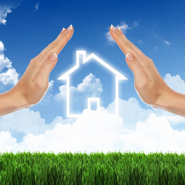 Ev ve mavi gökyüzü karşı insan eli — Stok fotoğraf