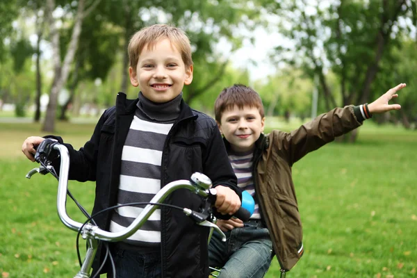 Jongen op een fiets in het groene park — Stockfoto