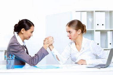 Young women arm wrestling in office clipart