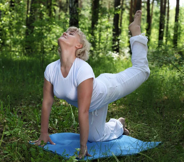 Yaşlı bir kadın yoga yapıyor. — Stok fotoğraf