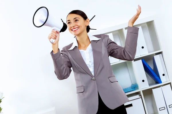 Young woman with megaphone in office — Stock Photo, Image
