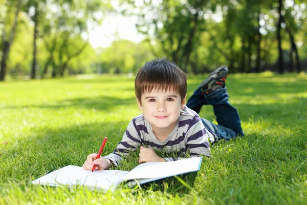 Портрет мальчика с книгой в парке — стоковое фото