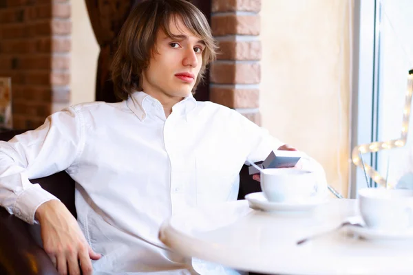 Młody przystojny mężczyzna siedzi w restauracji — Zdjęcie stockowe