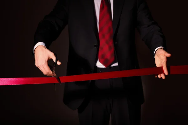 Businessman with scissors cuting a red ribbon — Stock Photo, Image