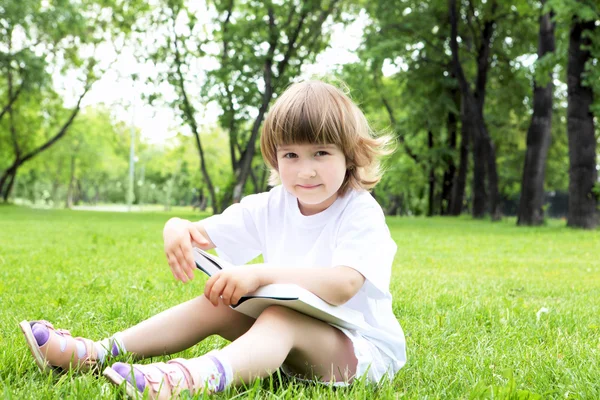 Portrét holčička čtení knihy v parku — Stock fotografie