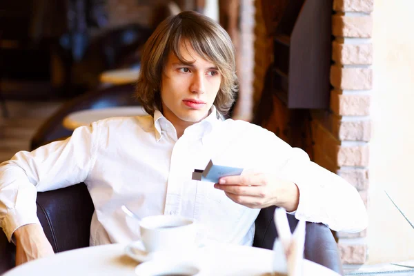 Junger schöner Mann sitzt im Restaurant — Stockfoto