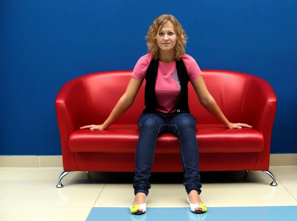 Junge Frau sitzt auf rotem Sofa — Stockfoto