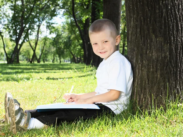Portrait d'un garçon avec un livre dans le parc — Photo
