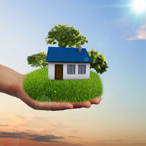 House and human hand against blue sky — Stock Photo, Image