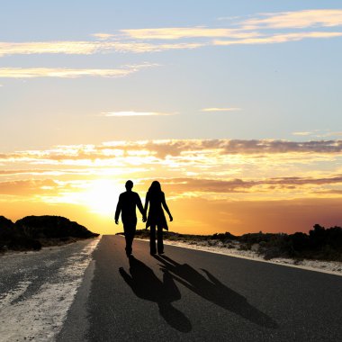 Man walking away at dawn along road clipart