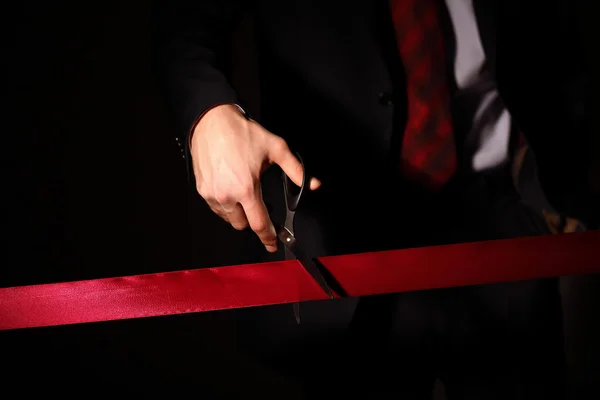 Biznesmen z cuting nożyczki czerwoną wstążką — Zdjęcie stockowe