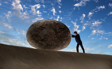 Businessman rolling a giant stone clipart