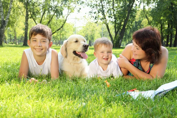 Madre y sus dos hijos en el parque con un perro —  Fotos de Stock