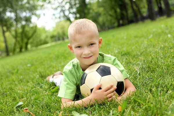 Маленький хлопчик в парку з м'ячем — стокове фото