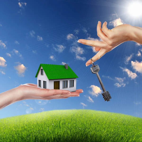 House and human hand against blue sky — Stock Photo, Image