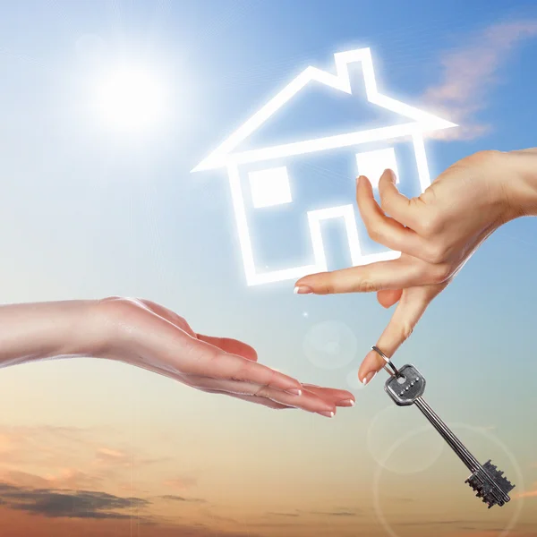 Huis en menselijke hand tegen blauwe hemel — Stockfoto
