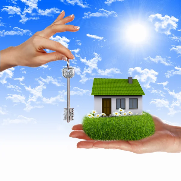 House and human hand against blue sky — Stock Photo, Image