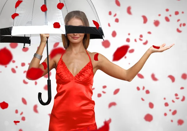 Vacker kvinna under paraply med kronblad runt henne — Stockfoto