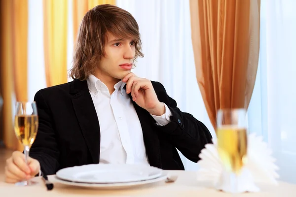 Jovem homem bonito sentado no restaurante — Fotografia de Stock