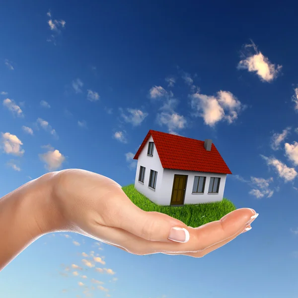Huis en menselijke hand tegen blauwe hemel — Stockfoto