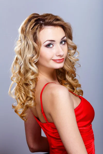 Ung kvinna i röd klänning med lockigt hår — Stockfoto