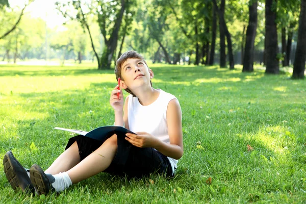 Retrato de un niño con un libro en el parque — Foto de Stock