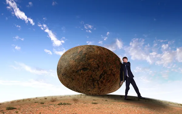 Uomo d'affari rotolando una pietra gigante — Foto Stock