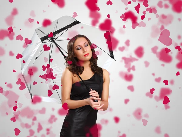 Hübsche Frau unter Regenschirm mit Blütenblättern um sich — Stockfoto