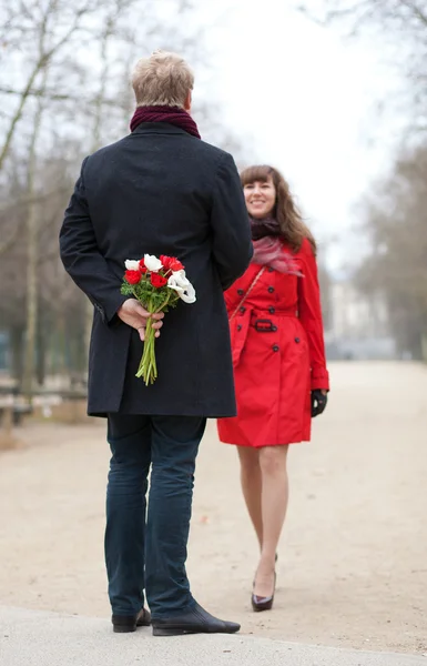 Coppia felice avendo un appuntamento, l'uomo sta per offrire fiori al suo — Foto Stock