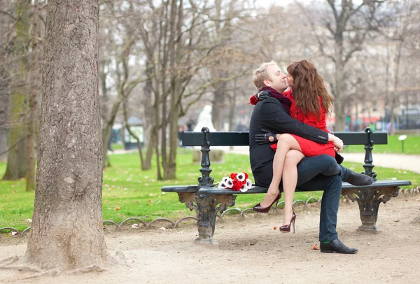 Šťastný romantický pár objímat a líbat na lavičce — Stock fotografie