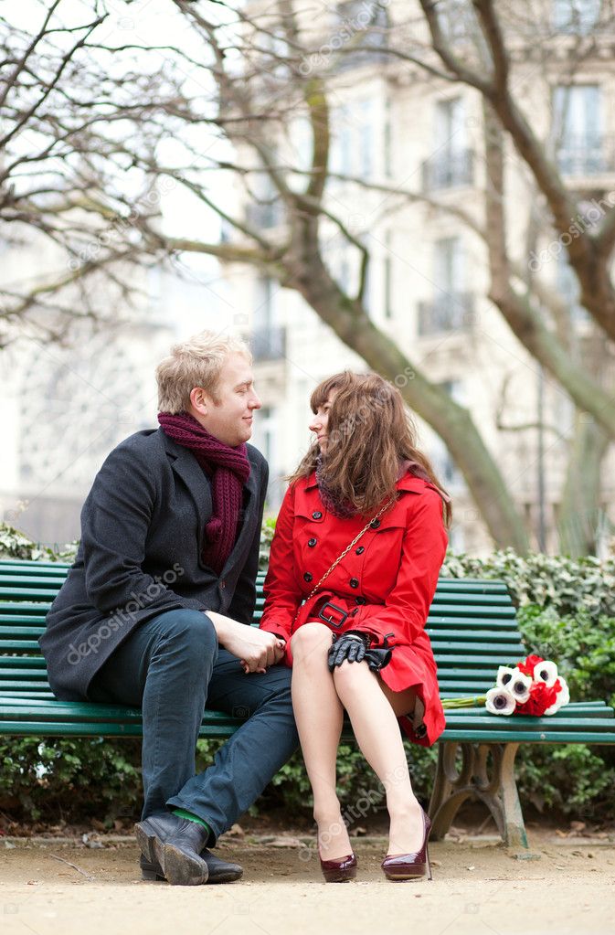 Dating couple sitting on a bench in Paris near the Notre Dame de