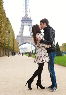 Young romantic couple kissing near the Eiffel Tower in Paris clipart