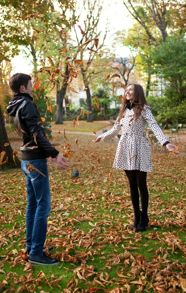Счастливая молодая пара играет с листьями осенью — стоковое фото