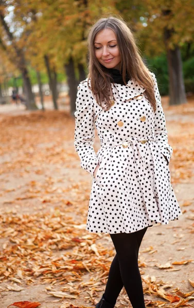 Beautiful young woman in polka dot trench at fall — Stock Photo, Image